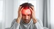 © Sajal.savar - Man experiencing a headache or migraine with hands on head and red glowing forehead
