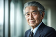 © EricMiguel - Japanese senior businessman with silver swept - back hair in navy pinstripe suit, contemplative gaze by office window in soft natural light