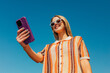 © VISTA by Westend61 - Smiling woman taking a selfie outdoors with smartphone in summer