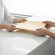 © logonv - Woman doctor handing yellow folder to female patient in clinic. Medical professional giving document or test result to client. Healthcare service, consultation and patient record exchange.