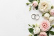 © Ekaterina - elegant flat lay of two wedding bands surrounded by white and pink blossoms on white background. ideal for wedding invitations, greeting cards, banners, or jewelry store promotional materials