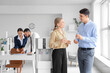 © Pixel-Shot - Young business colleagues with glasses of water near cooler in office