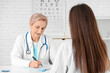 © Pixel-Shot - Happy mature female doctor filling laboratory report form for patient in clinic