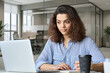 © insta_photos - Young indian female student working on laptop in modern office coworking space classroom. Hispanic business woman using computer watching virtual online training course, remote learning concept.