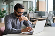 © insta_photos - Latin indian serious businessman wearing glasses and headset having virtual team meeting call, remotely working at home watching online learning training webinar in remote office.
