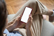 © insta_photos - Young woman or teen girl hands holding mobile smart phone with mockup white blank display, empty screen at home. Shopping, delivery apps, social media applications ads, over shoulder close up view.