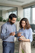 © insta_photos - Diverse friendly coworkers talking using digital tablet in office. Indian manager having discussion with latin employee meeting in office lobby discussing project, teaching new employee sharing ideas.