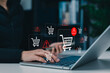© Sandwish - E-Commerce Warning and Shopping Cart Risk Concept. Woman using laptop with shopping cart icons and alert symbol, online purchase issues, checkout risk, transaction warning, ecommerce security concerns