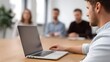 © Bussakon - Professional meeting with a laptop and blurred colleagues in a modern office setting