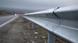 © photo for everything - A close-up view of a metal road safety barrier alongside a highway with a blurred background of distant vehicle lights and an overcast sky