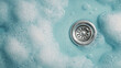 © Dzunstock - Close-up of a sink drain surrounded by blue soap bubbles and foam in a cleaning or washing context.