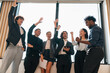 © chokniti - Business team celebrating success in office happy diverse professionals raising hands teamwork achievement corporate victory collaboration motivation workplace energy
