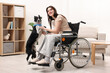 © New Africa - Woman in wheelchair and her service dog indoors