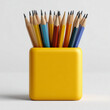 © RicardoLuiz - A vibrant collection of sharpened graphite pencils in various colors standing inside a bright yellow square pencil holder against a clean white background, ideal for school or office themes