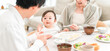 © buritora - Mothers and fathers feeding their babies solid food and meals at the dinner table (childcare/parenting)