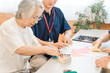 © buritora - A senior citizen and a male and female occupational therapist using cylinder pegs for hand function training during rehabilitation.