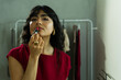 © AntonioDiaz - Latin model applying red lipstick in a changing room, preparing for an event or fashion show backstage, beauty routine