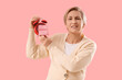 © Pixel-Shot - Displeased mature woman holding alarm clock with word MENOPAUSE on pink background