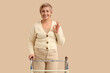 © Pixel-Shot - Mature woman with walker showing OK on beige background