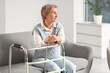 © Pixel-Shot - Mature woman with walker sitting on sofa at home