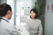© KANGWANS - Woman sits calmly, facing doctor in clinical setting. medical consultation concept