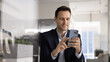© fizkes - Confident Hispanic business professional executive using mobile phone at office desk managing digital project writing email browsing information searching for expert insights on web interacting online