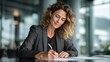 © Anat art - Professional Woman Signs Contract at Modern Desk in Bright Office Setting While Showing Focus and Satisfaction