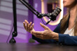 © fizkes - Closeup of female host talking into professional microphone during live discussion, knowledge or experience sharing. Podcast recording, content creation, broadcasting in modern creative studio concept