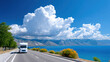 ©  VladaToday - Motorhome driving on open highway beside blue lake under dramatic cumulus clouds for travel banner and scenic road trip background