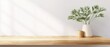 © pite - Wooden tabletop with shadow of leaves, beige wall background, copy space for product display, ideal for use in cosmetic branding, home decor, or as a backdrop for text.