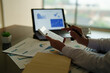 © Tj - Accountant or analyst hands calculating numbers with a calculator and pointing at financial reports and graphs on a laptop screen, managing budget and investment planning in an office setting