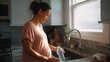 © Frank Gärtner - Pregnant woman filling a reusable water bottle in her kitchen, focusing on hydration and healthy lifestyle