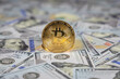 © Gautier Normand - Gros plan sur une pièce bitcoin dorée, posée sur des billets en dollar, symbolisant les devises numériques et papiers.