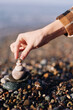 © SHOTPRIME STUDIO - Balance, stones, hand, beach, pebbles, zen, mindfulness, harmony, stacking, meditation scene with a gentle hand placing stones on a rock tower by the shore