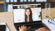 © Prostock-studio - Young woman works on laptop at home. She types on keyboard during video call with multiple people on screen. Focus is on her hands and the laptop showing the online meeting.