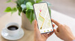 © Prostock-studio - Cropped of woman using navigation mobile app on smartphone, using tracking service, order taxi online. Unrecognizable lady drinking coffee at home, waiting for cab, panorama