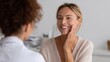 © Fiverr/fazilazia703 - Smiling woman client touches her cheek, showing satisfaction during a dermatology or beauty consultation with a professional.
