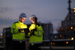 © Apichat - Engineers collaborating using tablet at industrial refinery at night
