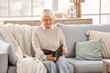 © Pixel-Shot - Christian senior woman reading Holy Bible on sofa at home