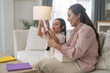 © Art_Photo - Asian happy mother reading handmade greeting card from little daughter on sofa, Cute child giving gift box to mom, Mother's Day celebration, sweet family bonding, childcare and warm love life concept