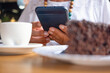 © luciano - Close up of senior woman relaxing for a break at coffee shop in mall using mobile phone enjoying a coffee cup and a slice of cake.