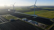 © AmazingAerialAgency - Aerial view of Windplan Groen wind farm with wind turbines, agricultural fields, and a canal in Dronten, Flevoland, Netherlands.