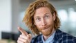 © OleksandrZastrozhnov - Young caucasian male with long red hair and beard pointing finger playfully in office setting