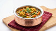 © Food Shop - A copper bowl filled with vegetable curry on a wooden cutting board and red cloth isolated on white background