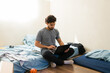 © AntonioDiaz - College student struggling with new independent life, making ends meet in first apartment, sitting on floor working with laptop