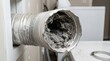 © DailyLens Studio - Close up view of a severely clogged silver flexible dryer vent hose filled with dangerous lint and dust in a home laundry room showing a serious fire hazard