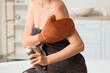 © Pixel-Shot - Young woman with massage glove applying self tanner mousse in bathroom, closeup