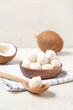 © Pixel-Shot - Wooden spoon and bowl with delicious coconut candies on white table