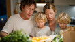 © forenna - Kitchen counter covered with unpaid utility notices and empty grocery bags while family of four eats simple pasta dinner together, perfect for income struggle and contemporary resilience theme cinem