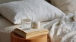 © GATE 22 - Wooden nightstand with a stack of books and a glass of water on top of it. the nightstand is placed on a bed with white sheets and pillows.